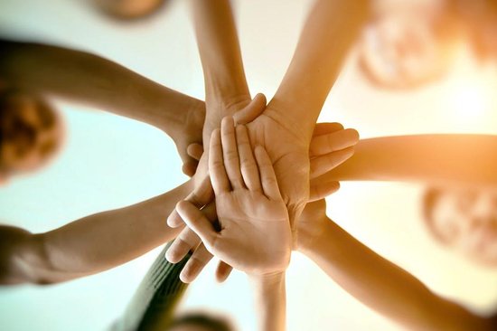 tím držiaci ruky na kope znázorňujúci jednotu